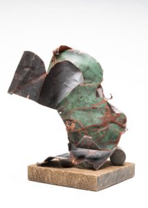 On a roll Image is of a three dimensional copper sculpture of twisted metal with a partially green patina mounted on a wood base.